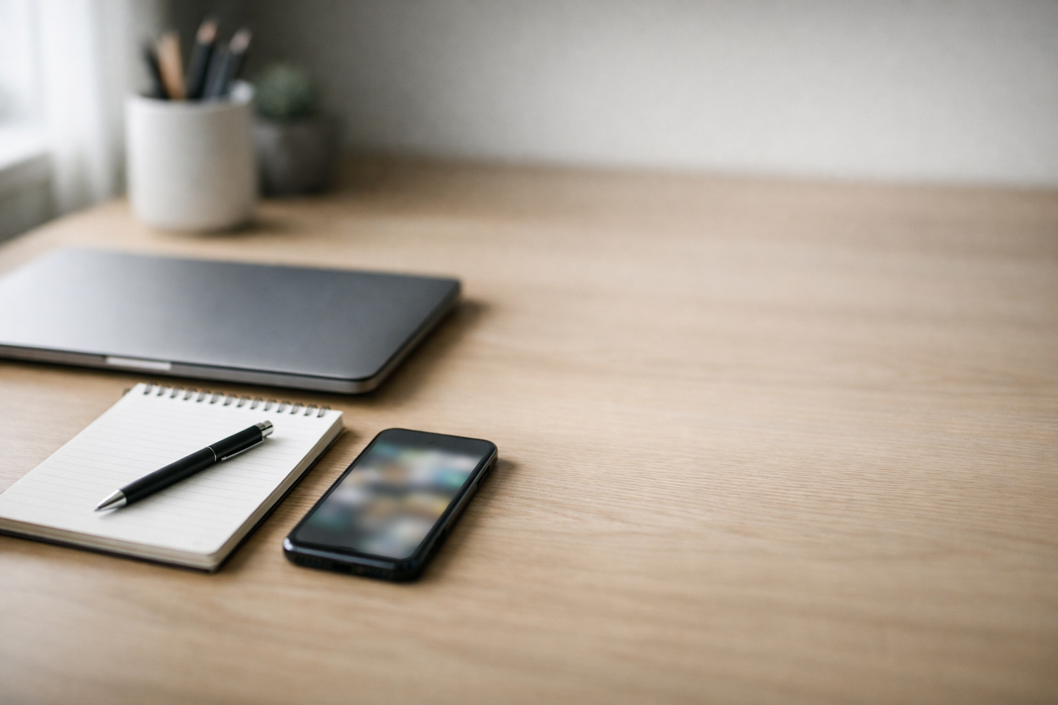 Minimal modern desk setup with laptop, notepad, and phone representing building trust before a sales call