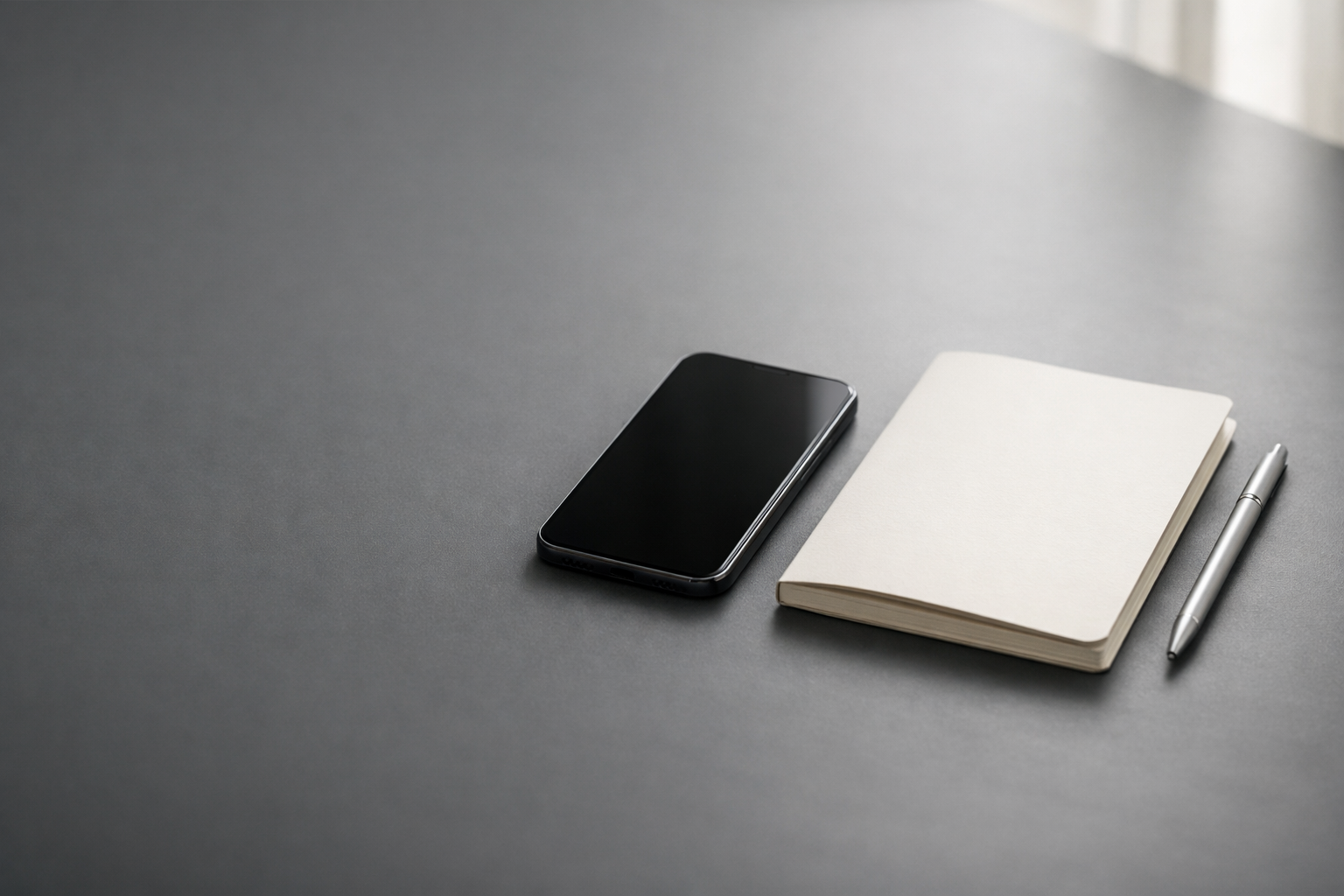 Minimal professional desk scene with a smartphone and notebook, representing Instagram Reels scripting for qualified inquiries