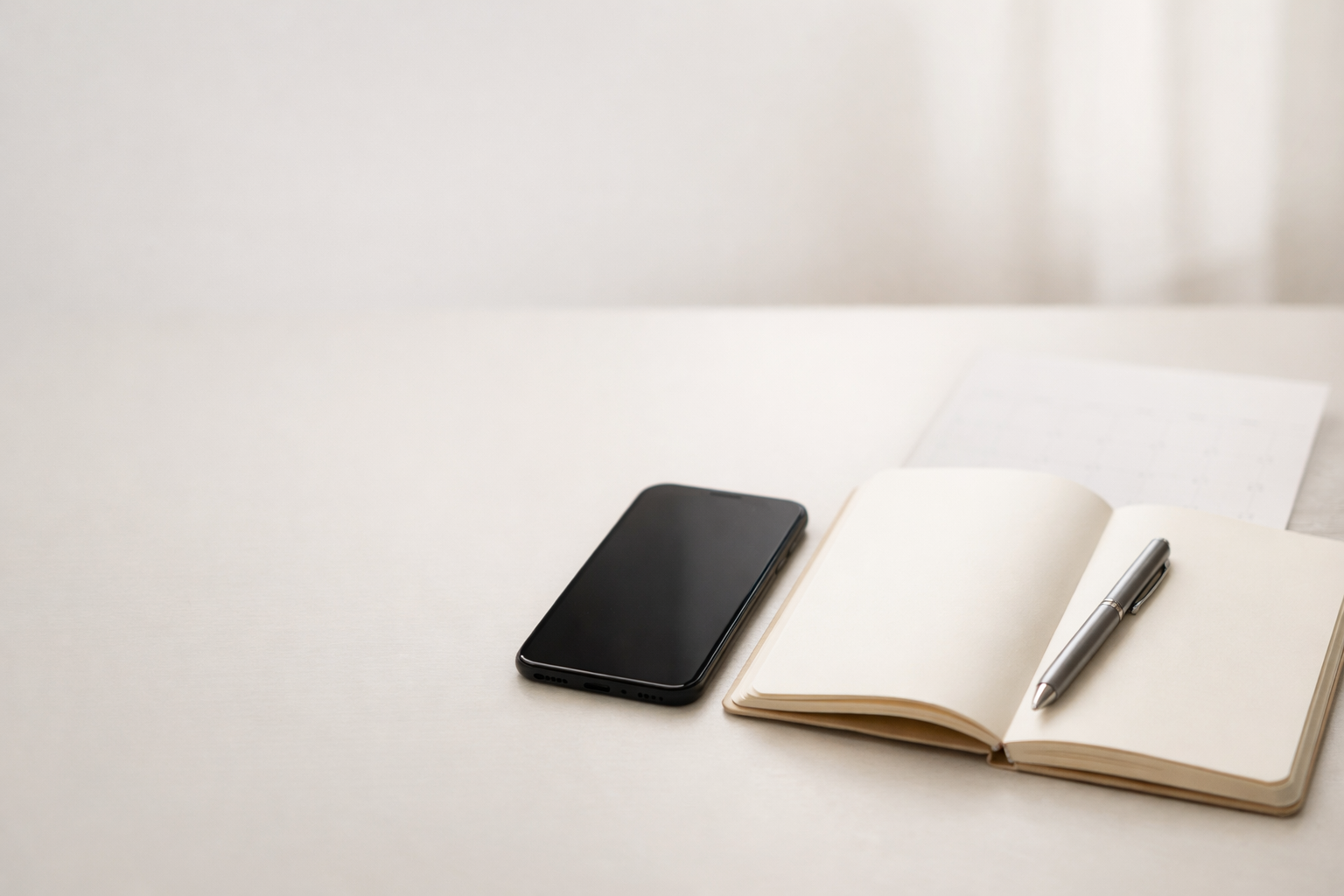 Clean desk setup with smartphone, notebook, and pen representing a strategic social media content plan.